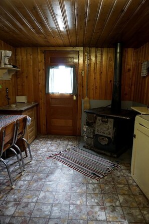 Un interior de madera con una zona de cocina, que incluye una estufa, sillas y una mesa.