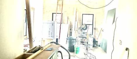 A narrow hallway with wooden beams on the ceiling, a ladder, and various tools and equipment.