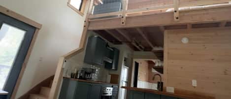A loft-style bedroom with a wooden ceiling, a small window, and a bed.