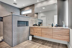Ein modernes Badezimmer mit großem Spiegel, Holzschrank und strukturierter Wand.
