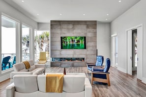 A modern living room with a large flat-screen TV, comfortable seating, and a fireplace. - Elegant Amelia Island Family Beach Home (Fernandina Beach)