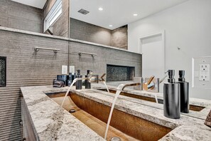 Ein modernes Badezimmer mit Marmorplatte, integrierter Dusche und großem Spiegel.