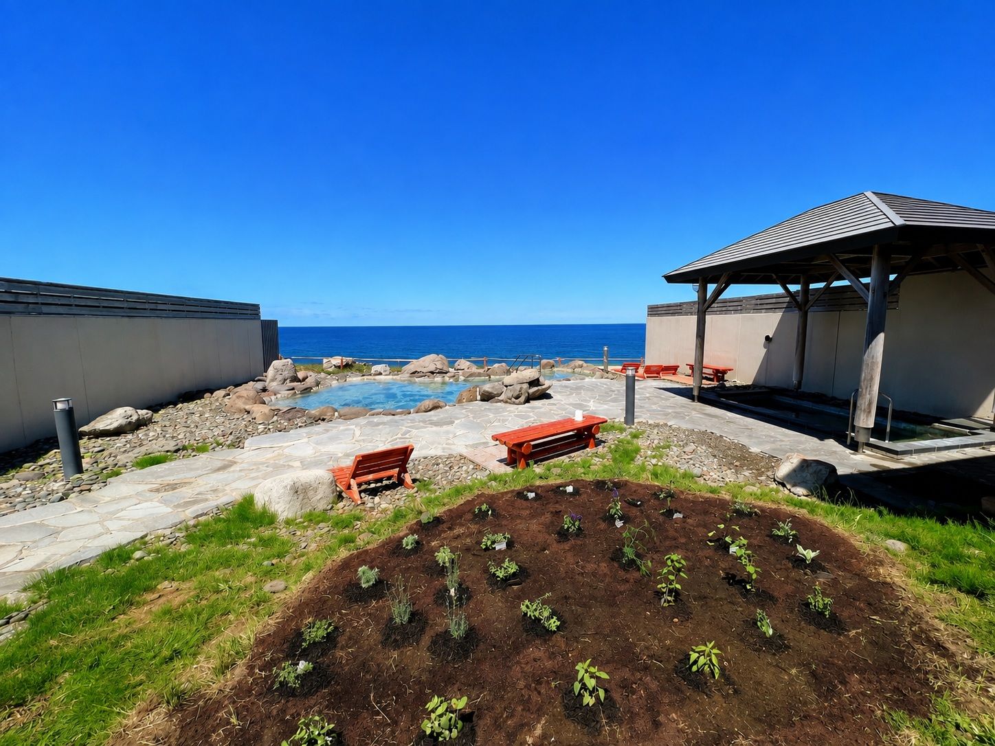 A rooftop garden with a swimming pool, seating areas, and a view of the ocean.