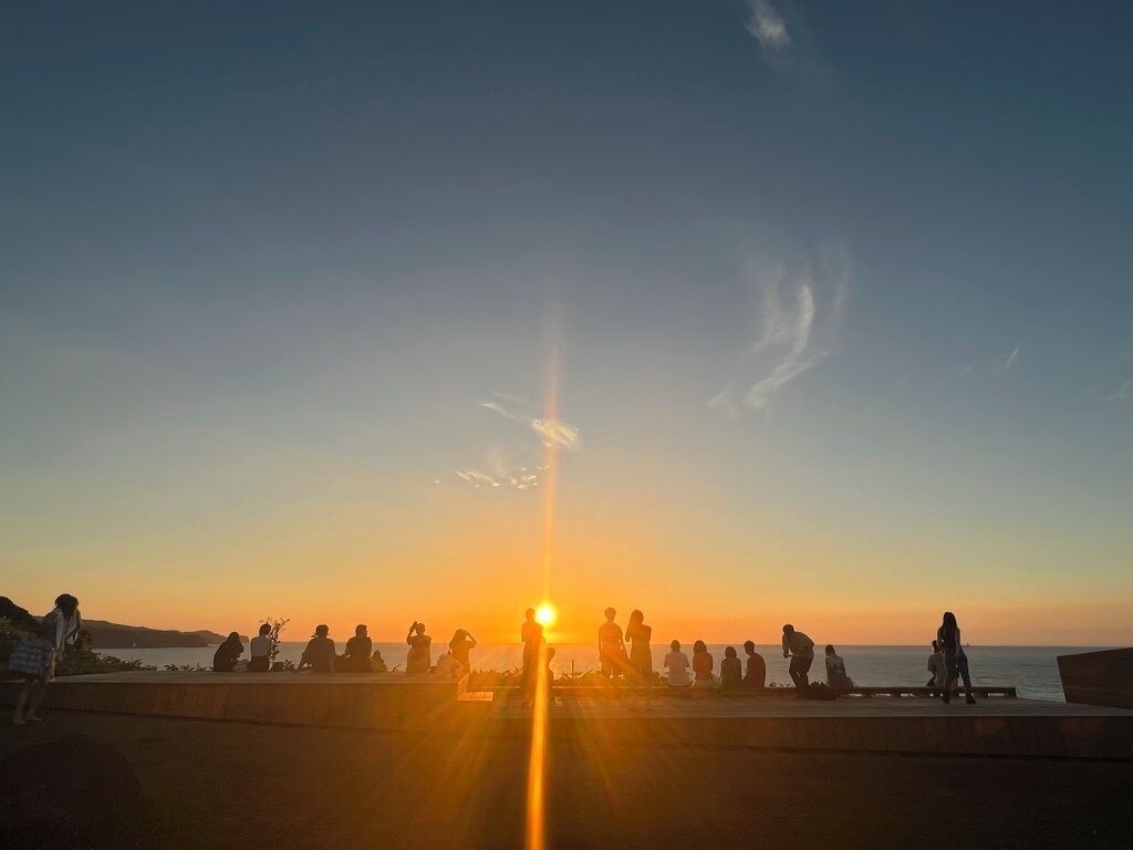 A sunset over a body of water with people sitting on a pier.