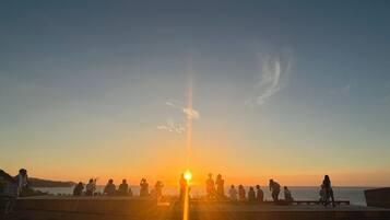 A sunset over a body of water with people sitting on a pier.