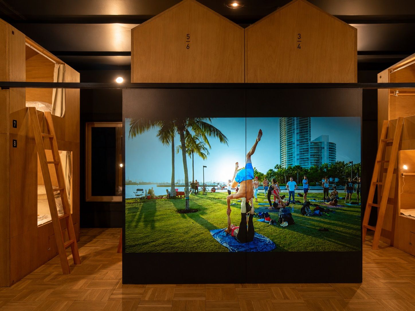 A room with bunk beds, a large digital display, and wooden paneling.