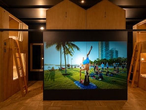 A room with bunk beds, a large digital display, and wooden paneling.