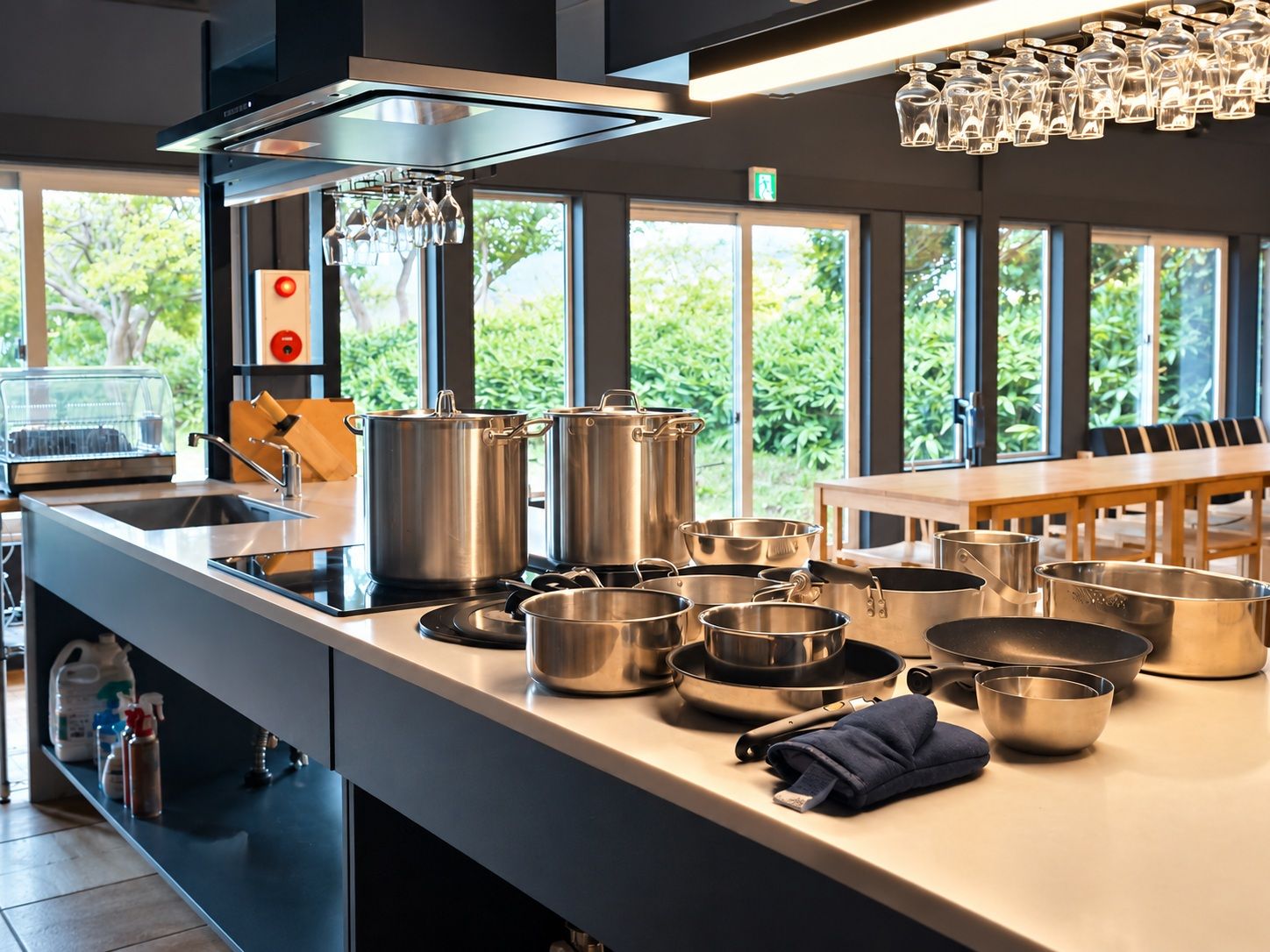 Una cocina moderna con electrodomésticos de acero inoxidable, una isla grande con ollas de cocina y vistas a zonas verdes a través de amplios ventanales.