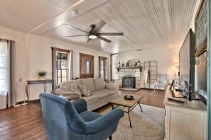 A living room with a sofa, two armchairs, a fireplace, a television, and a ceiling fan. - Luxurious German-Style Ranch Vacation Rental with Pool Access and Stunning Views in Bergheim, Texas (Bergheim)