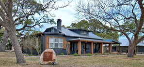 Une maison avec un toit en métal, une cheminée et une véranda dotée de sièges extérieurs.