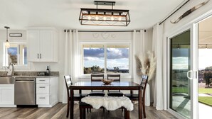 Uma cozinha moderna com armários brancos, uma mesa de jantar de madeira e uma janela grande com vista para o exterior.
