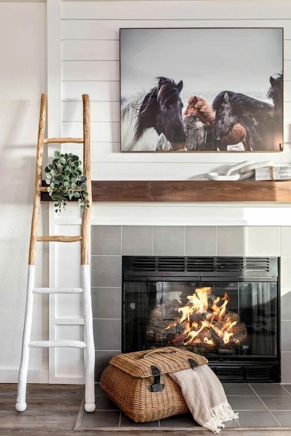 Una chimenea con fuego, un televisor montado encima y una escalera de madera apoyada en la pared.