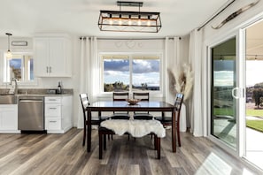 Una cocina moderna con armarios blancos, una mesa de comedor de madera y un ventanal con vistas al exterior.
