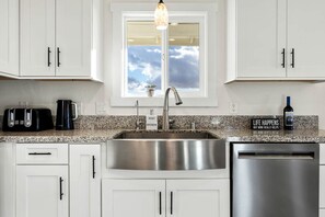 A kitchen with white cabinets, a stainless steel sink, a toaster, a coffee maker, and a wine bottle. - Heavenly Vacation Retreat with Sweeping Vineyard Views near Paso Robles Wineries in California (Paso Robles)