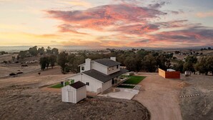 Uma casa de dois andares com um amplo jardim frontal, uma garagem e um pequeno galpão.