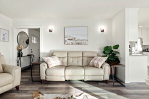 Una sala de estar con un sofá color beige, una mesa de comedor y una zona de cocina.