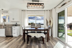 Una cocina moderna con armarios blancos, una mesa de comedor de madera y un ventanal con vistas al exterior.