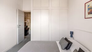 Una camera da letto con un letto, un comodino, una lampada a parete e un quadro incorniciato.