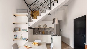 Una cucina moderna con mobili bianchi, una porta nera e un'area pranzo con tavolo apparecchiato per due persone.