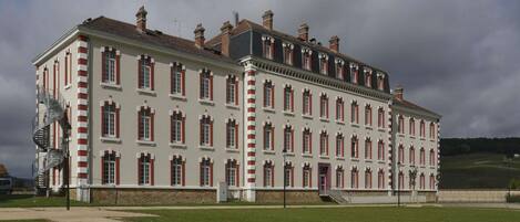 A large, historic building with a symmetrical facade, multiple chimneys, and a central staircase.