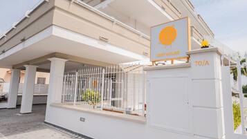 Un bâtiment blanc avec une enseigne indiquant « ZEST HOUSE » et un portail portant le numéro « 70/A ».