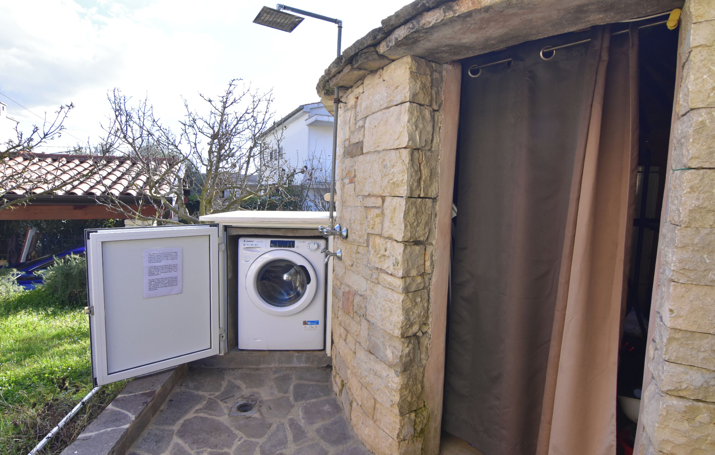 A laundry area with a washing machine and dryer, a stone wall, and a covered entrance.