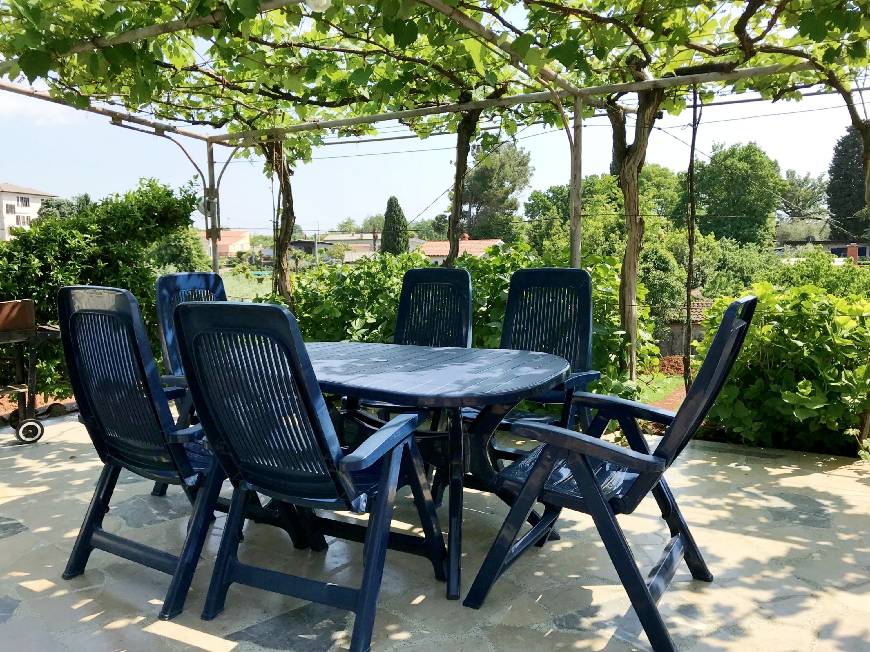 Un espace extérieur abrité, aménagé avec une table ronde et six chaises.