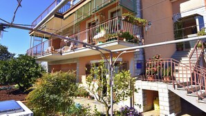 Un edificio residencial de varios pisos con balcones, plantas en macetas y una escalera visible.
