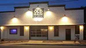 A building with a sign reading 'Old Main Ice House' and a neon 'OPEN' sign. - Deluxe Safari Tent Cabin with Creek Swimming, Fishing & Resort-Style Amenities in Marion, Texas (Marion)