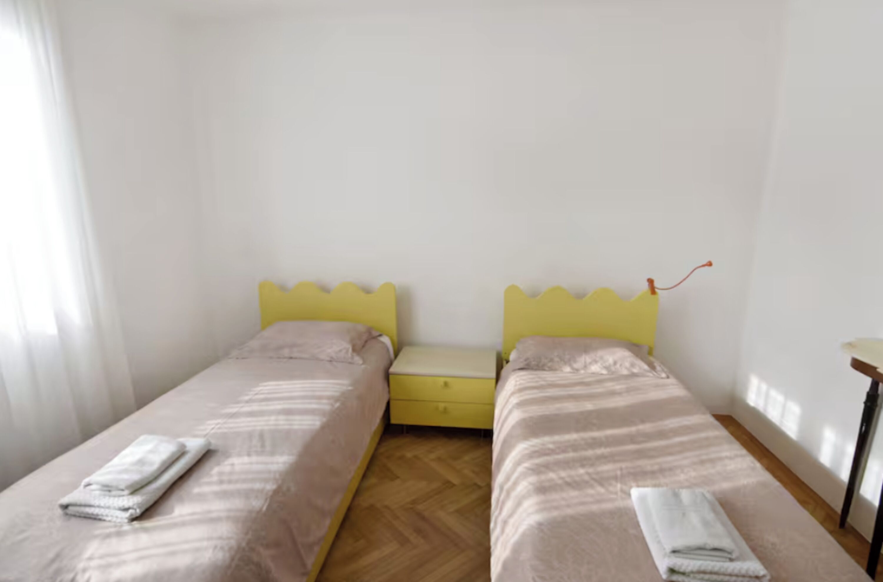 Une chambre avec deux lits simples, une petite table de chevet et une fenêtre.