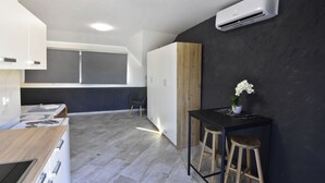 A modern kitchen with white cabinets, a wooden table, and a black countertop. - Cozy holiday flat for two (Plovanija)