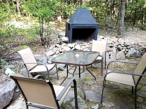Un espace extérieur aménagé avec un foyer en pierre et des chaises en métal.