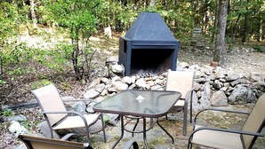 Un espace extérieur aménagé avec un foyer en pierre et des chaises en métal.