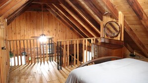 Un intérieur en bois comprenant un lit, un luminaire suspendu et un escalier en bois.