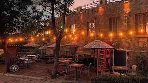 An outdoor dining area with tables and chairs, string lights, and umbrellas. - Assos Elit Pansiyon (Ayvacik)