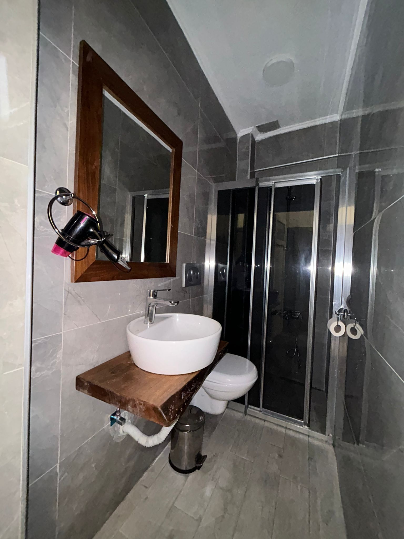 A bathroom with a white sink, a mirror, a shower, and a toilet.