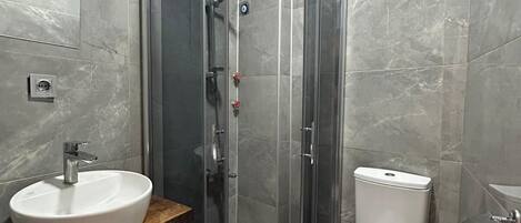 A modern bathroom with a glass-enclosed shower, a white sink, and a toilet.