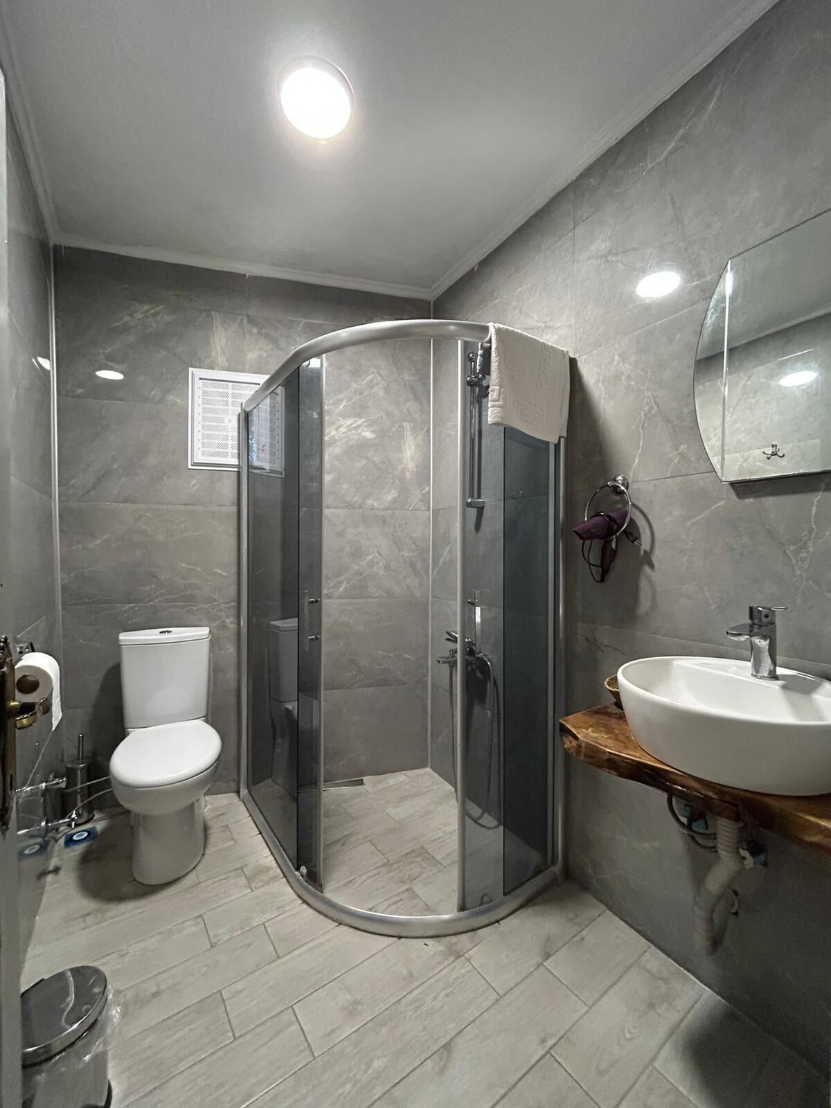 Um banheiro moderno com box de vidro, vaso sanitário e pia com bancada de mármore.