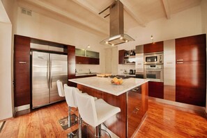 A modern kitchen with a central island, stainless steel appliances, and wooden cabinetry. - Valletta Postcard Penthouse (Il-Belt Valletta)