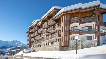 A multi-story hotel with balconies, stone walls, and a snow-covered landscape.