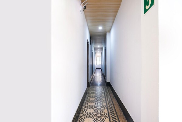 Un pasillo largo y estrecho con piso estampado y paredes blancas.