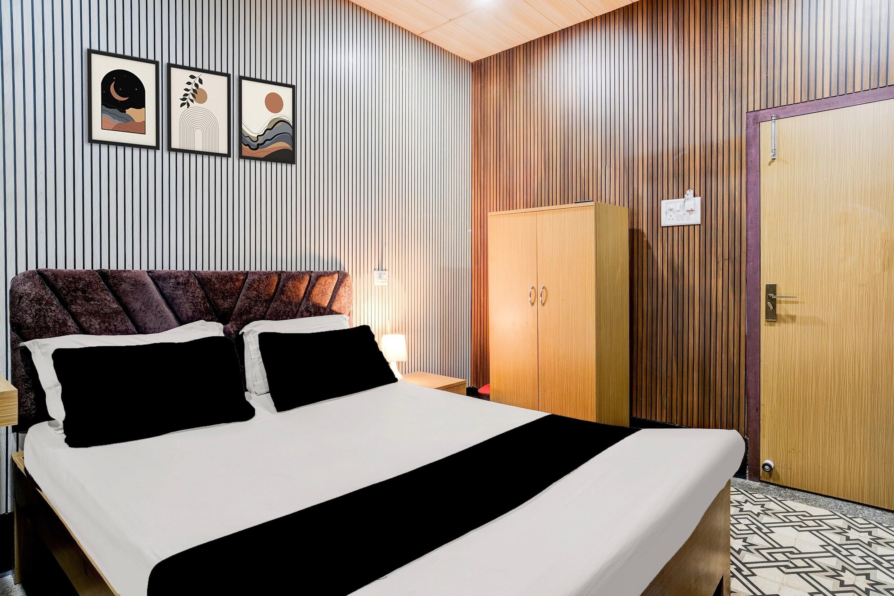 Una habitación de hotel con una cama, un armario y tres cuadros en la pared.