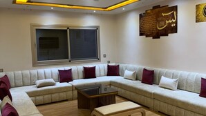 Una sala de estar con un sofá modular, una mesa de centro y una ventana con persianas.