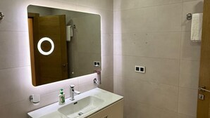 Un baño con un espejo grande, un lavabo y una zona de ducha.