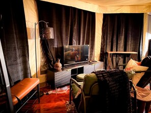 Un salon confortable avec un téléviseur, un canapé, un fauteuil et une lampe.