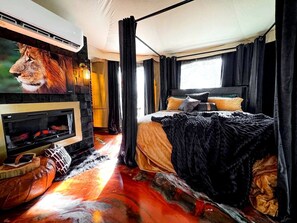 Ein Zimmer mit Kamin, einem Bett und einem großen Fenster.