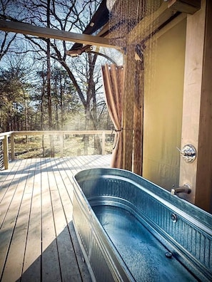 A wooden deck with a hot tub, a wooden door, and a metal railing.