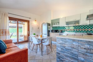A modern kitchen with a dining area, a sofa, and a sliding glass door leading to an outdoor patio. - [Center - 1 km from the sea] Villa Relax with Garden (Sardegna, Provincia della Gallura Nord-Est Sardegna)