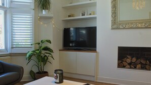 Ein Wohnzimmer mit Fernseher, Blumentopf, Zeitschrift auf einem Couchtisch und Kamin.