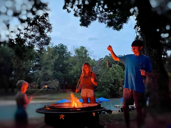 A group of people around a campfire in a wooded area.